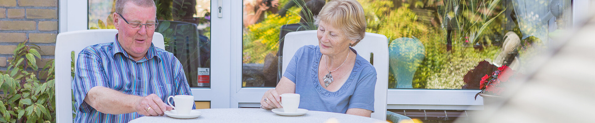 Oudere mensen met kopje koffie in de tuin